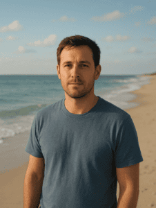 Man standing on the beach with ocean and sky in background.